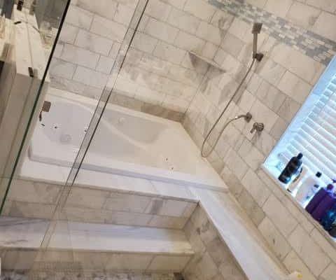 Luxurious bathroom remodel in Palm Beach featuring a marble-tiled shower and bathtub, showcasing elegant custom renovation work.