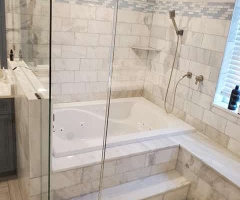 Luxurious custom bathroom renovation featuring a modern glass shower, elegant marble tile, and built-in bathtub in Palm Beach home remodeling project.