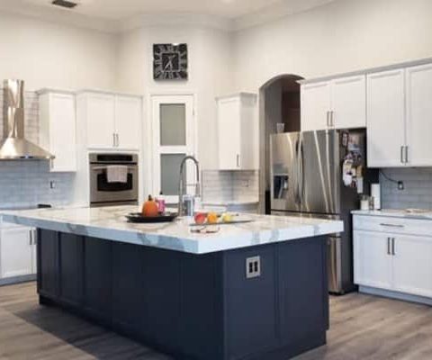 Modern kitchen renovation with white cabinets, stainless steel appliances, and a large central island in Palm Beach home remodeling project.