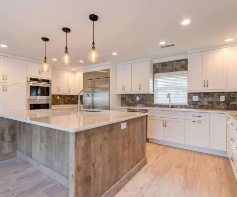 Modern kitchen remodel featuring a spacious island with marble countertop, pendant lighting, and white cabinetry in Palm Beach. Custom renovation by expert remodeling team.