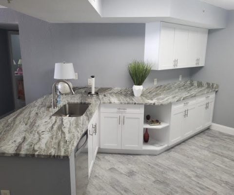 Modern kitchen remodel with elegant granite countertops and white cabinetry in Palm Beach home renovation.