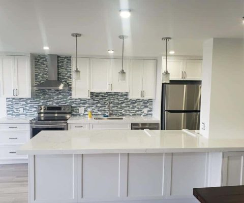 Modern kitchen renovation in Palm Beach featuring sleek white cabinetry, stainless steel appliances, and a stylish mosaic tile backsplash. Perfect example of custom kitchen remodeling and home design.